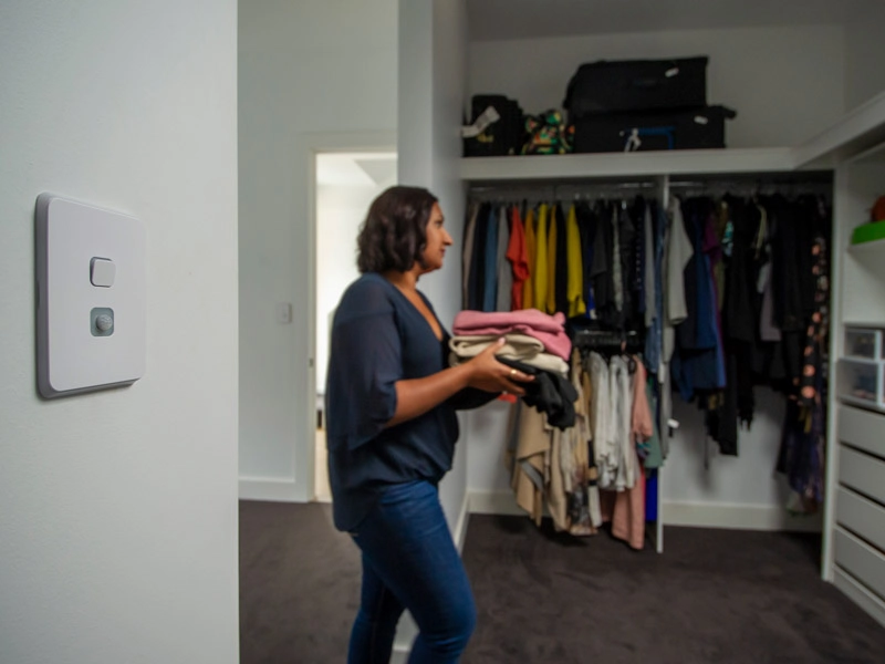 A woman with a piece of clothing walking to the closet