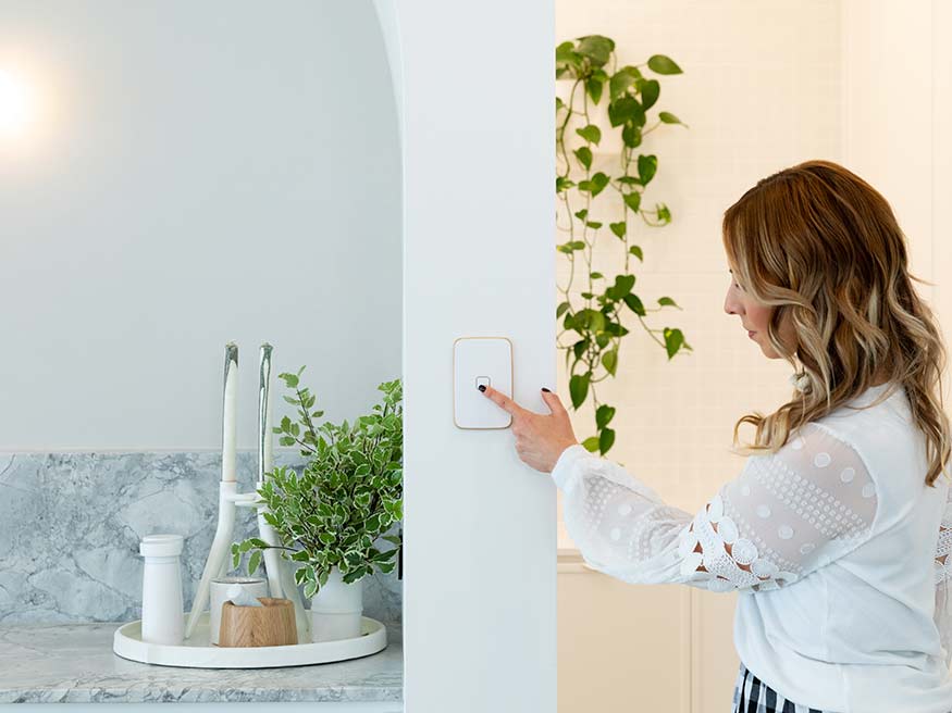 Woman presses the on button of Iconic Essence arctic white switch