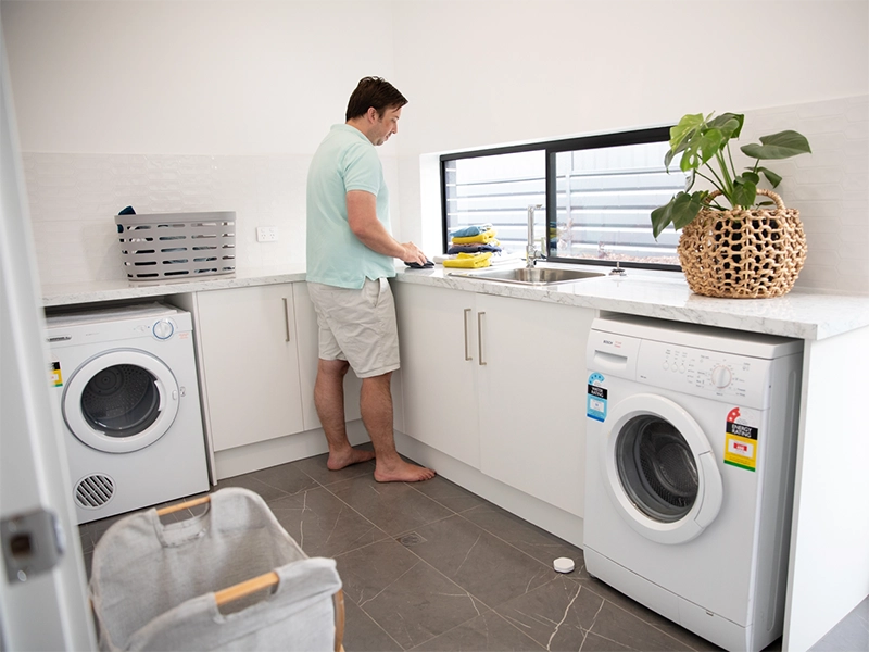 A man standing in a kitchen next to a washer and dryer