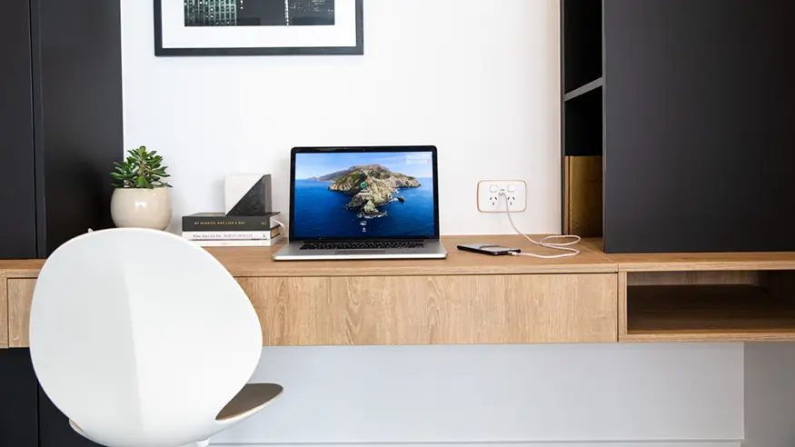 Open laptop on a light colored wooden desk.