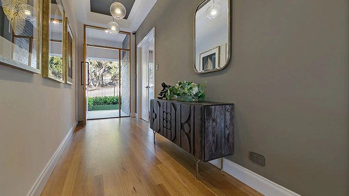 Hallway featuring a large mirror and polished wooden flooring