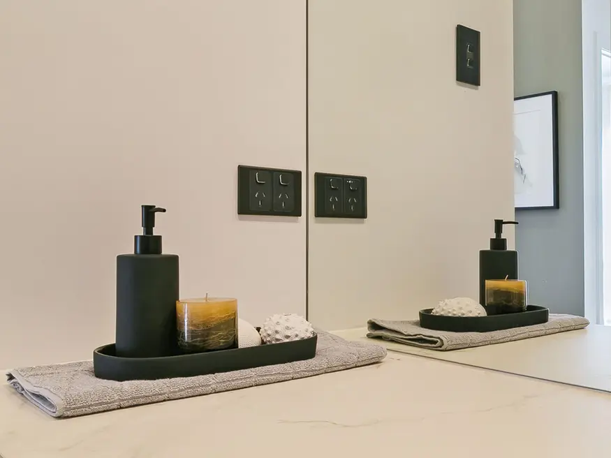 Bathroom counter with soap dispenser and candle on a tray.