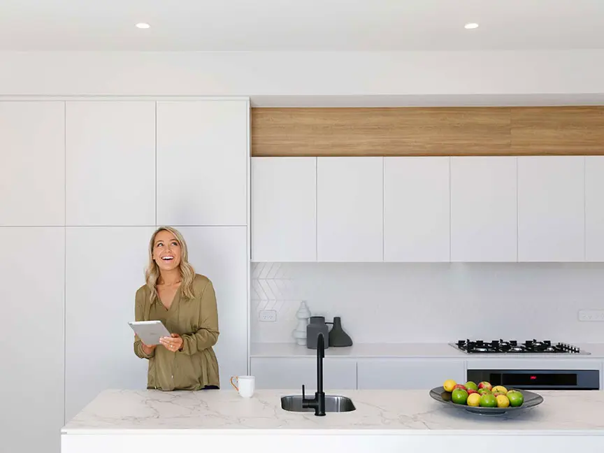 Happy woman in kitchen holding her iPad.