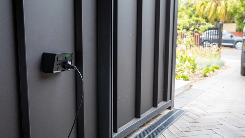 Black electric outlet securely plugged into a wall socket