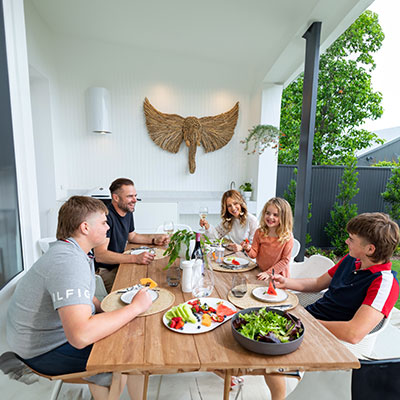 A group of people eating at a table in a backyard