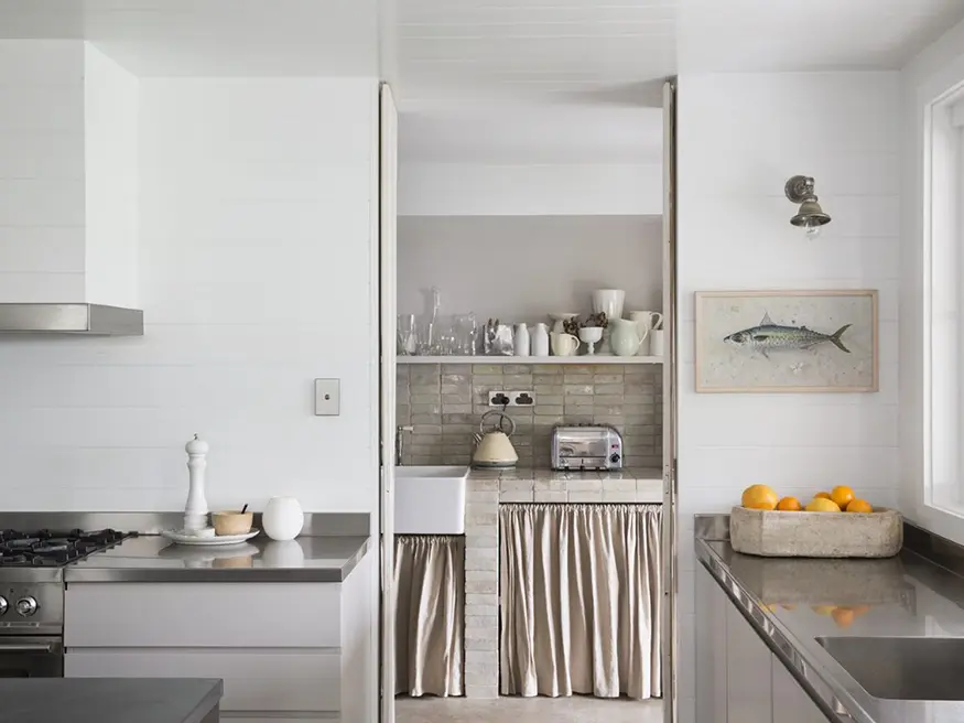 A clean kitchen with a sink, a toaster oven, and a painting of a fish on the wall.