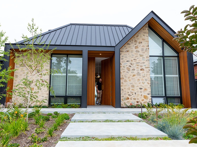 Contemporary home featuring a stone facade and a sleek black roof