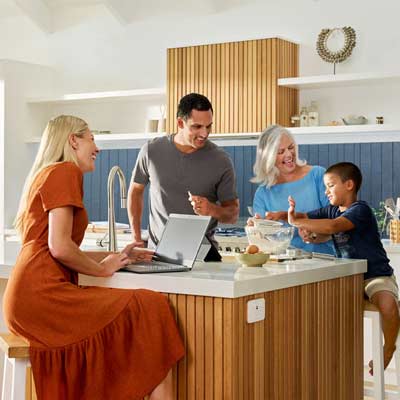 A family of four enjoying quality time in their kitchen while using a laptop.