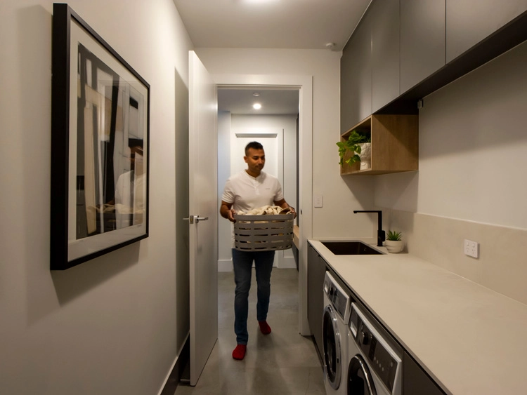 A man holding a laundry basket in a kitchen