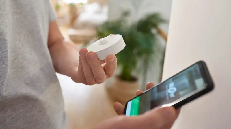 Man holding a motion sensor and a phone