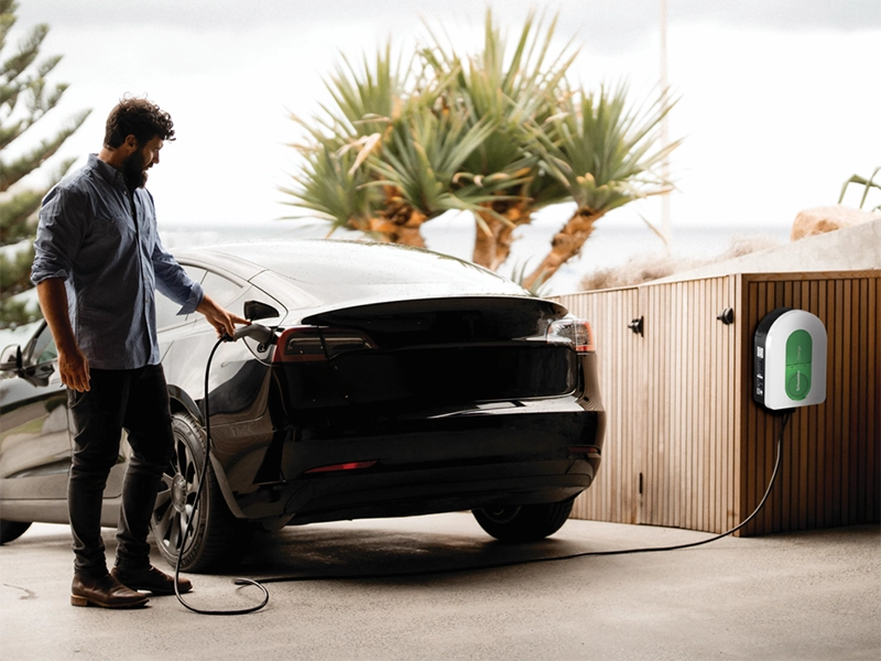 Man connects a charging cable to his electric car at garage