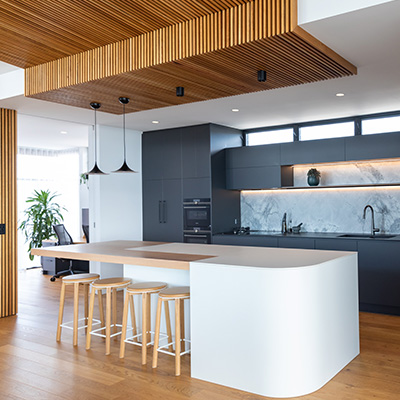 Modern kitchen with beautiful wooden slated ceiling and pendant lights over the island