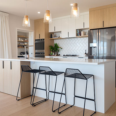 A modern kitchen with a sleek white counter top and stylish black stools.