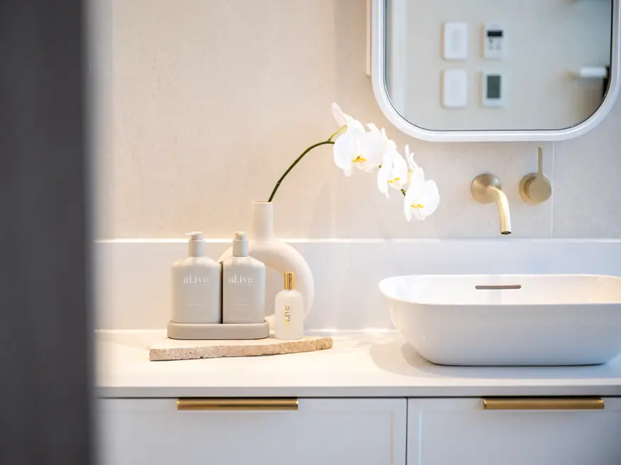 White bathroom with a single sink and a round mirror.