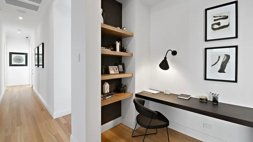 Modern workspace with sleek desk, shelves, and chair.