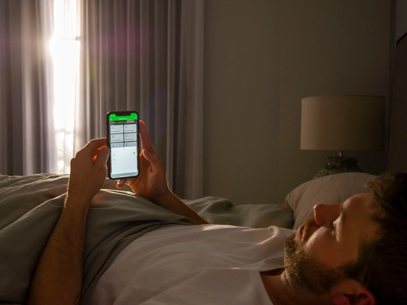 A man resting in a bed and scrolling through an app