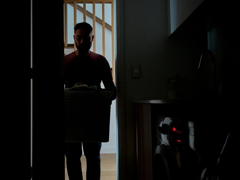 Man entering in a dark room while holding a laundry basket